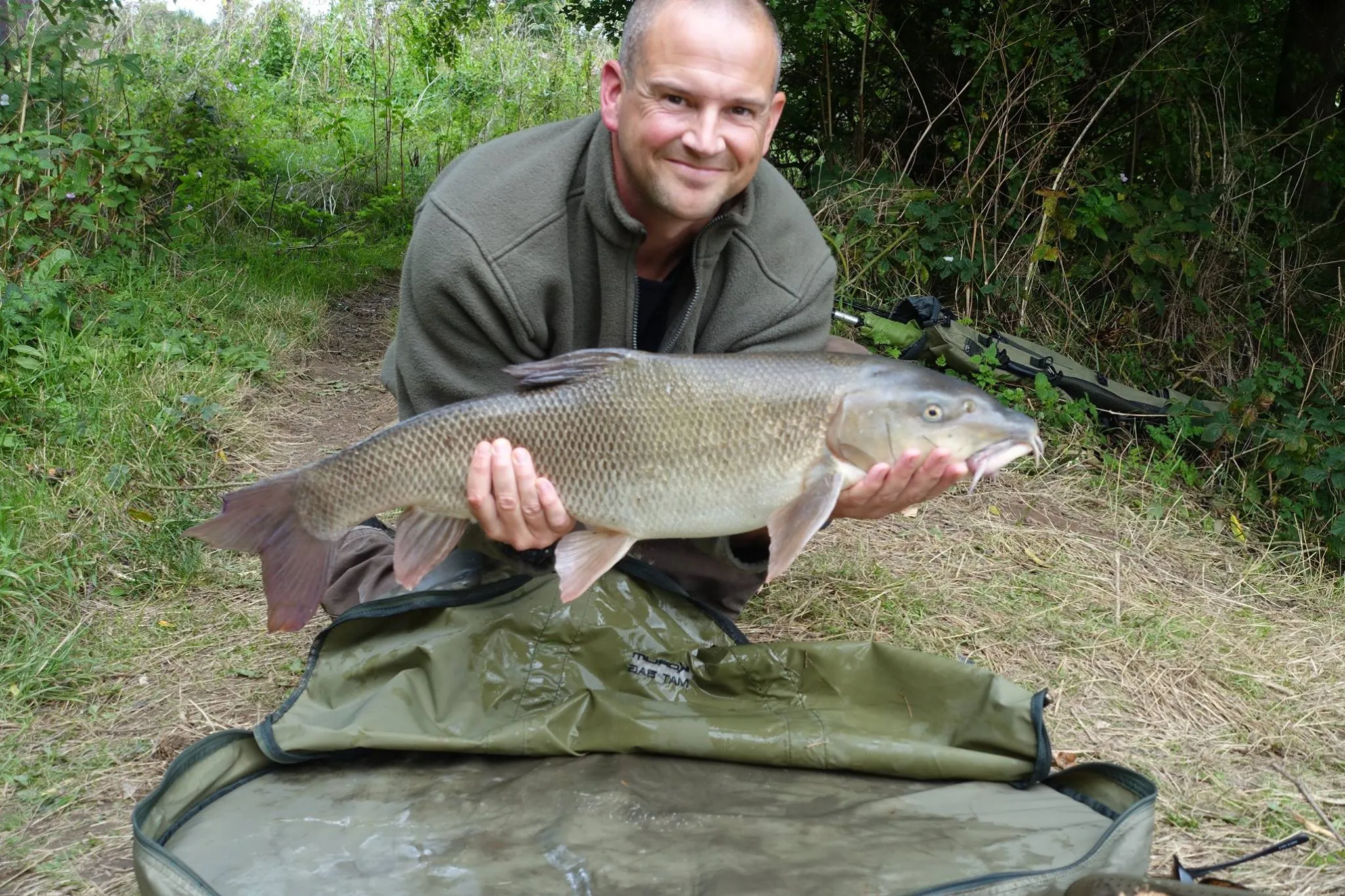 A member kneeling with an 11lb barbel on an unhooking mat